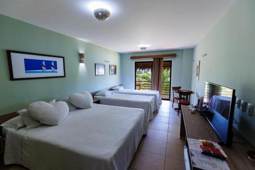 um quarto de hotel com duas camas e uma mesa em Carnaubinha Praia Resort em Luis Correia