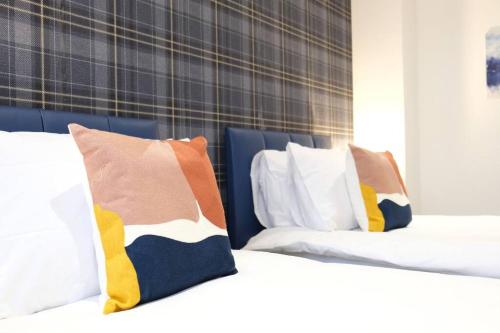 two beds with colorful pillows on top of them at Prime Location - 4 Bedroom 3.5 Bathroom House - Sleeps up to 8 - Free Parking, Fast Wifi, Balcony, Smart TV and Private Garden by Yoko Property in Milton Keynes