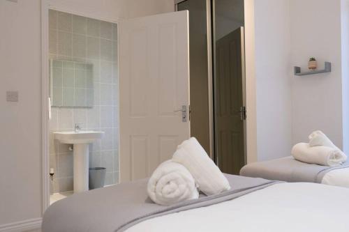 a bedroom with two beds and a bathroom with a sink at Prime Location - 4 Bedroom 3.5 Bathroom House - Sleeps up to 8 - Free Parking, Fast Wifi, Balcony, Smart TV and Private Garden by Yoko Property in Milton Keynes