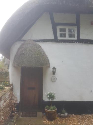 a white building with a brown door and a window at Delightful 3bed thatched Cottage in Stockbridge