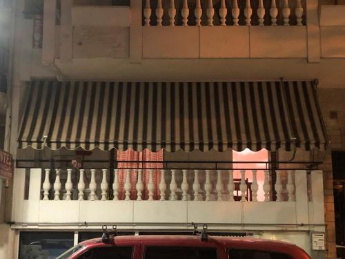 toldo en un edificio con un coche rojo aparcado delante en Small flat with everything near metro, en Pireo
