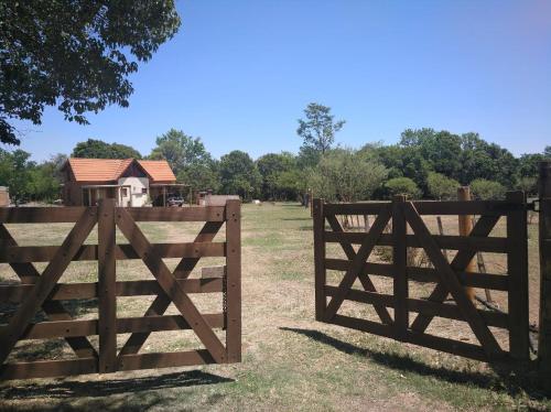 ein Holztor auf einem Feld mit einem Haus dahinter in der Unterkunft Cabañas el Ñato in Nono