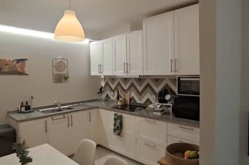 a kitchen with white cabinets and a sink and a microwave at Areia StayInn Beach Apartment in Árvore