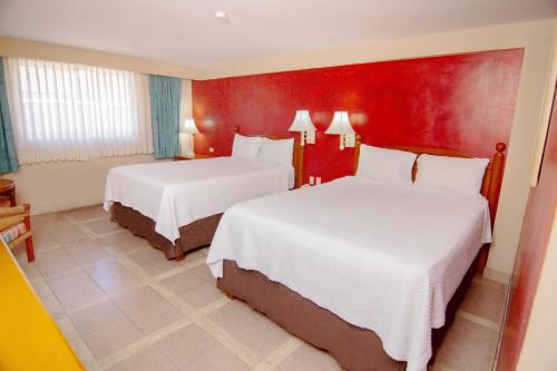 a hotel room with two beds and a red wall at Hotel Armida Guaymas in Guaymas