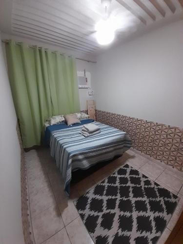 1 dormitorio con 1 cama con cortinas verdes y alfombra en Apartamento no centro de Cuiabá a 4 km do aeroporto, en Cuiabá