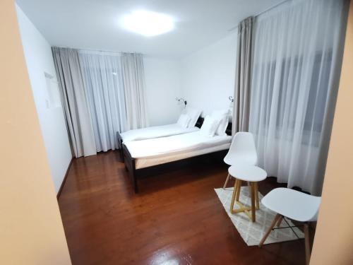 a bedroom with a bed and two white chairs at La Rocca in Fundata