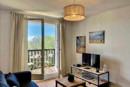 un salon avec un canapé et une grande fenêtre dans l'établissement Appartement Lassay - Welkeys, à Blonville-sur-Mer