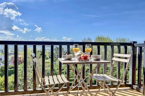 - une table avec deux verres de vin sur le balcon dans l'établissement Appartement Lassay - Welkeys, à Blonville-sur-Mer
