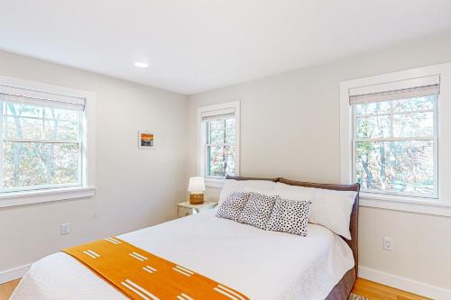 1 dormitorio blanco con 1 cama y 2 ventanas en The Saffron Cottage, en Wellfleet