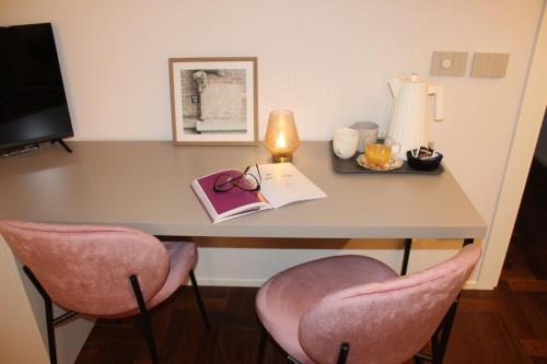 a desk with a book and two pink chairs at Coco21 in Modena