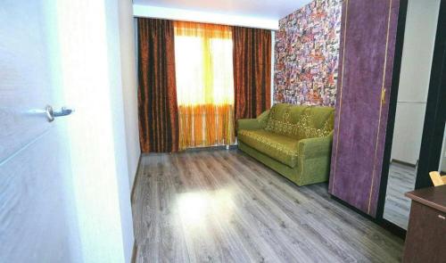 sala de estar con sofá verde y ventana en VIP apart 379, en Tiflis