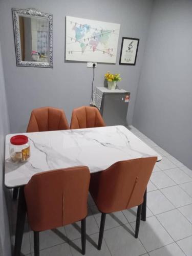 a white table with orange chairs in a room at Orchid Homestay in Labuan