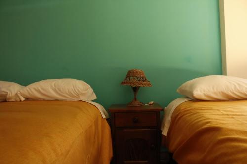 a bedroom with two beds and a lamp on a night stand at Casa D´Maria in Ollantaytambo