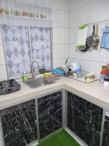 a kitchen with black marble counters and a sink at Orchid Homestay in Labuan