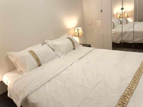 ein weißes Bett mit weißen Kissen und einem Spiegel in der Unterkunft Scandpoint Apartment Fornebu Near Sea front with outdoor walk! in Stabekk