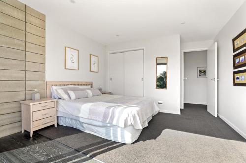a bedroom with a white bed and a wooden wall at Lake Tarawera Gem in Rotorua