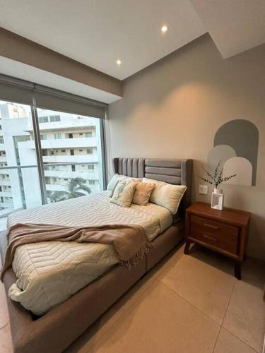 a bedroom with a large bed and a window at Departamento Cielo Bucerias, Beach Front Nayarit in Bucerías
