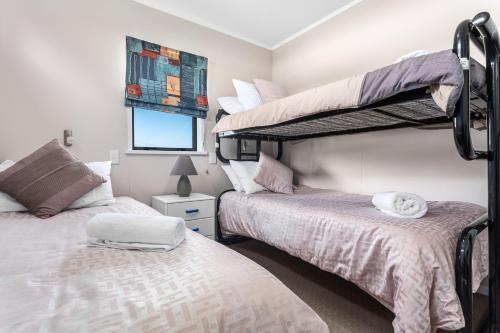 a bedroom with two bunk beds and a window at The Sun Capsule - Ohope Beach Holiday Home in Ohope Beach