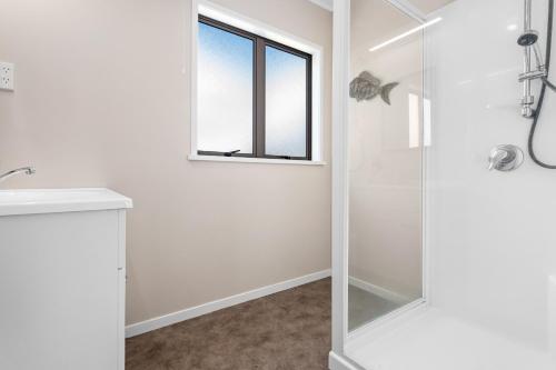 a white bathroom with a shower and a window at The Sun Capsule - Ohope Beach Holiday Home in Ohope Beach