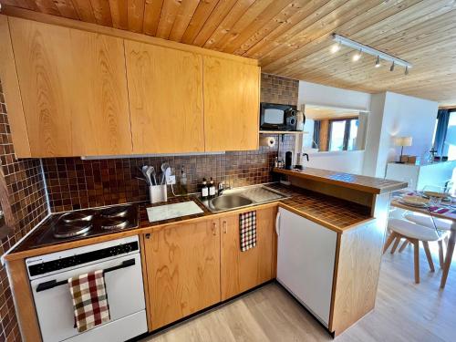 uma cozinha com armários de madeira, um lavatório e um fogão em THE ALPINE STUDIO on the ski slopes - by the lake - Alpe des Chaux - Gryon em Gryon