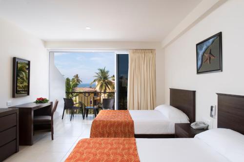 a hotel room with two beds and a balcony at Costa Club Punta Arena - Desayuno Incluido in Puerto Vallarta