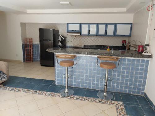 cocina con encimera de azulejos azules y taburetes en Ground floor villa with private garden, parking and shared swimming pool, en Al ‘Ajūzah