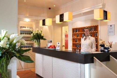 a man is standing behind a counter in a restaurant at Dorint Strandresort & Spa Westerland/Sylt in Westerland (Sylt)