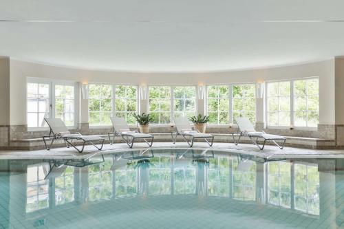 a large pool in a building with chairs and windows at Dorint Strandresort & Spa Westerland/Sylt in Westerland (Sylt)