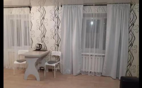 Zimmer mit einem weißen Tisch, Stühlen und Vorhängen in der Unterkunft VIP apart 384 in Tbilisi City