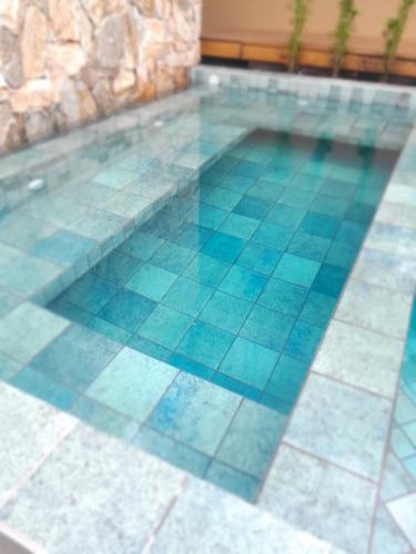 a swimming pool with blue tiles on the floor at Pousada Kirana in Praia do Rosa