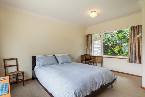 Schlafzimmer mit einem Bett und einem Fenster in der Unterkunft Kohekohe Garden Cottage - Waikanae Holiday Home in Waikanae