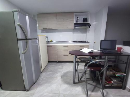 a small kitchen with a table with a laptop on it at Ninfa del Mar Hostal in Manizales