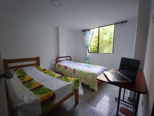 a bedroom with two beds and a laptop on a desk at Ninfa del Mar Hostal in Manizales