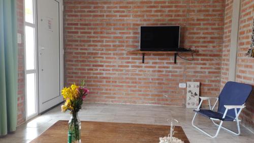 uma sala de estar com uma parede de tijolos e uma televisão em Casa de Playa em Playas Doradas