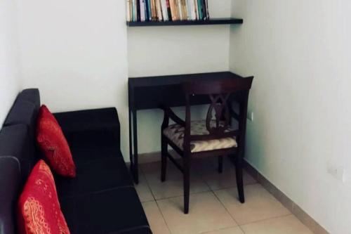 ein Wohnzimmer mit einem schwarzen Sofa und einem Stuhl in der Unterkunft Loft Plaza Belgrano in San Miguel de Tucumán