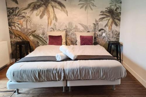 a bedroom with a bed with a tropical wallpaper at Maison et studio indépendant - Chez Lulu in Vertou