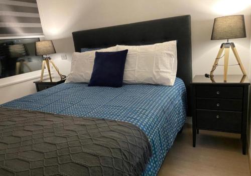a bedroom with a bed with a blue comforter and two lamps at Departamento Excelente Ubicación in Concepción