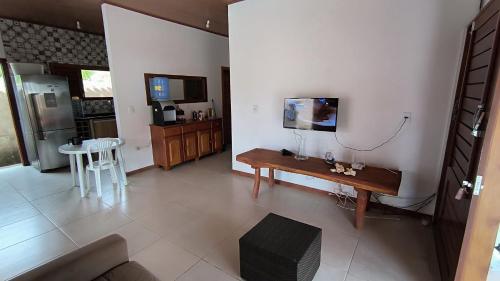 sala de estar con mesa y TV en la pared en Recanto São Miguel dos Milagres, en São Miguel dos Milagres