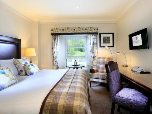 1 dormitorio con cama, escritorio y ventana en Macdonald Morlich Hotel at Macdonald Aviemore Resort en Aviemore