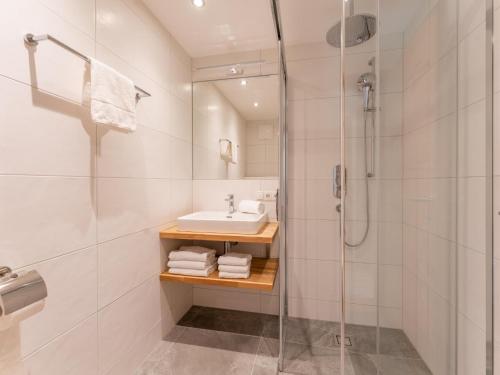 a white bathroom with a shower and a sink at Schmittenblick 4 in Viehhofen