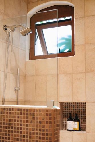 a bathroom with a shower and a sink with a window at Los Pilares Hotel in Oaxaca City