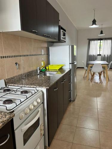 a kitchen with a stove and a refrigerator and a table at Departamento TALA - excelente nivel, con patio in San Fernando del Valle de Catamarca