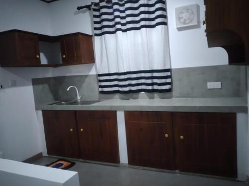 a kitchen with a sink and wooden cabinets at Cosy Holiday Home in Jayarajapuraya