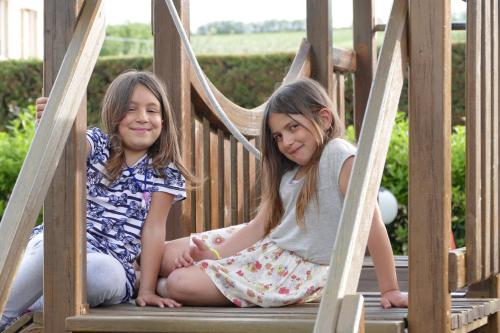two young girls sitting in a wooden play structure at Il Portico in Fano