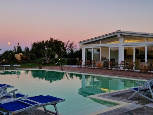 a swimming pool with two chairs and a house at 309 Le Saline - Stintino in Stintino