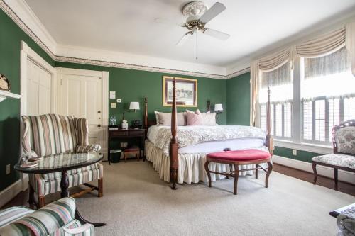 um quarto com paredes verdes e uma cama e uma cadeira em The Oaks Victorian Inn em Christiansburg