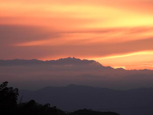 a sunset with clouds and mountains in the background at Bosques de la Pradera in Manizales