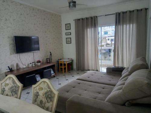 uma sala de estar com um sofá e uma televisão de ecrã plano em Locação Casa Residencial Guarujá - Alta Temporada no Guarujá