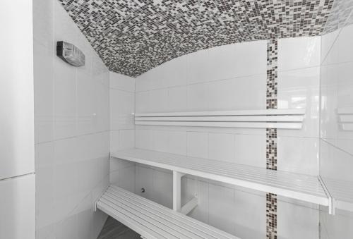 a white bathroom with a bench and a ceiling at Noosa International Resort in Noosa Heads