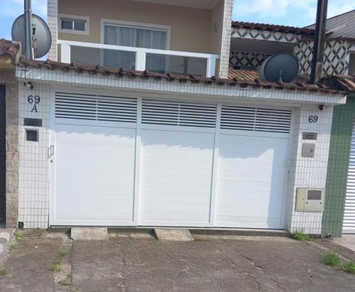 a pair of white garage doors on a house at Locação Casa Residencial Guarujá - Alta Temporada in Guarujá